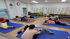 파란색 매트를 깔고 누워 전문 안마사에게 안마를 받고 있는 노인들 모습