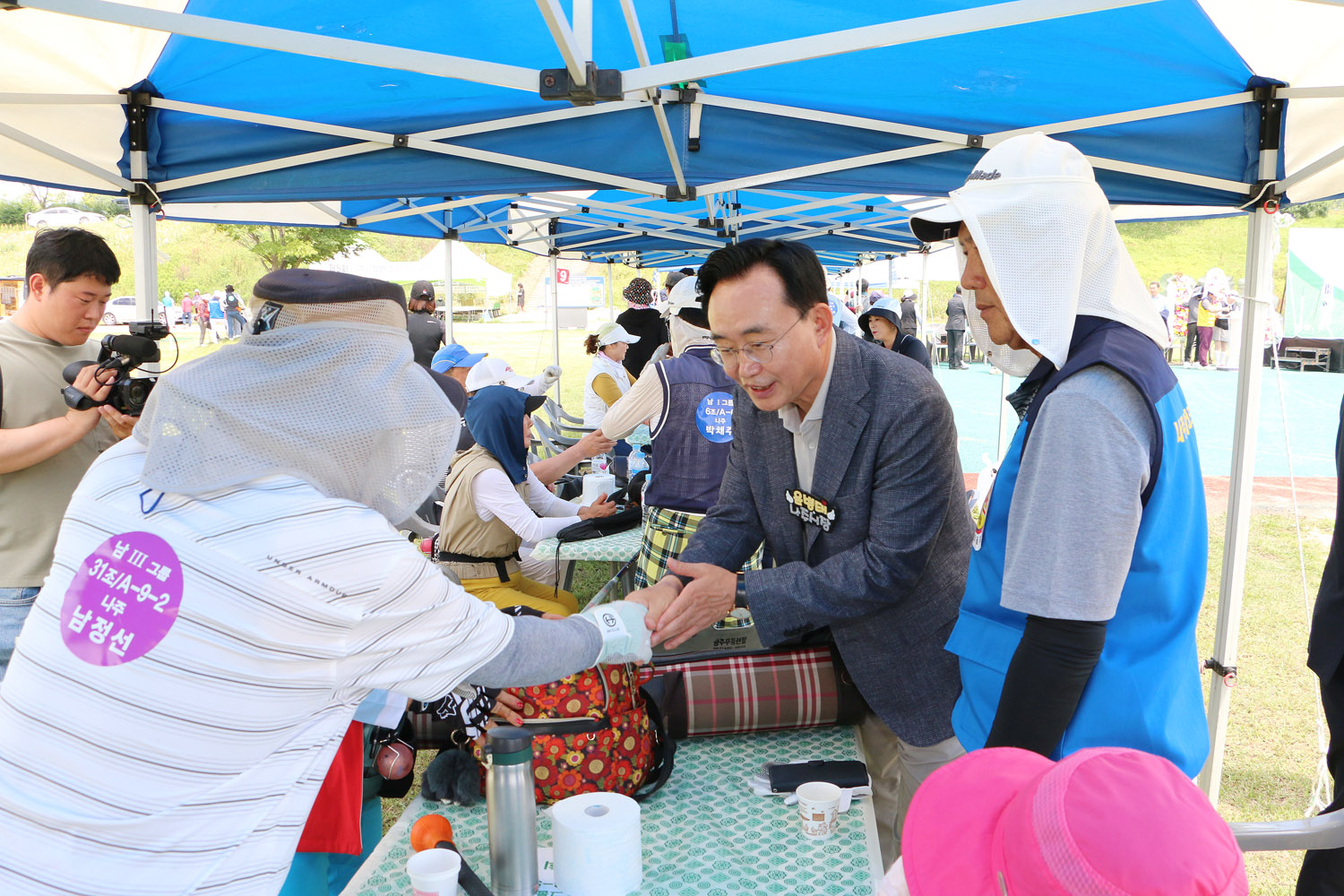 제5회 나주시장배 전남파크골프대회 나주시장이 행사장 부스에서 참석자와 악수를 나누며 인사를 하고 있는 모습