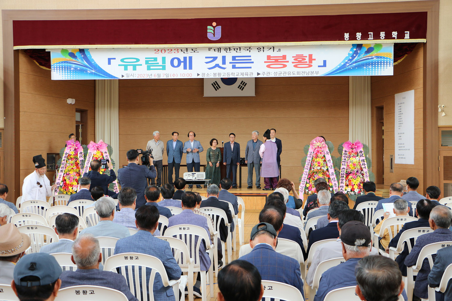 성균관유도회 전남본부 대한민국 읽기 행사 참석자들의 앉아있는 뒷 모습이 보이고 무대 위 시상자들이 서 있는 모습