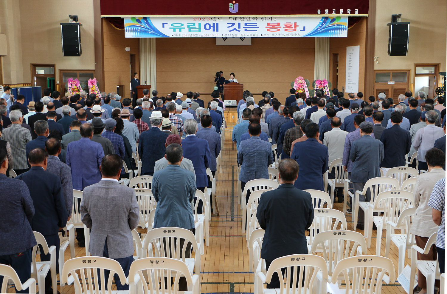 성균관유도회 전남본부 대한민국 읽기 행사 행사장 뒷쪽에서 참석자들의 서 있는 모습과 행사장 전면 모습