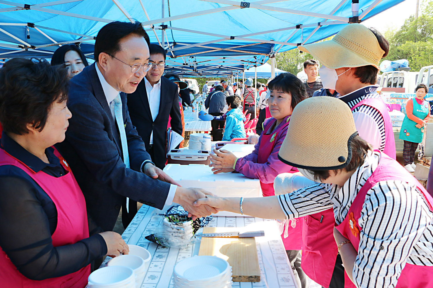 제39회 봉황면민의 날 행사 나주시장이 음식을 준비하는 여자 주민과 악수를 나누는 모습