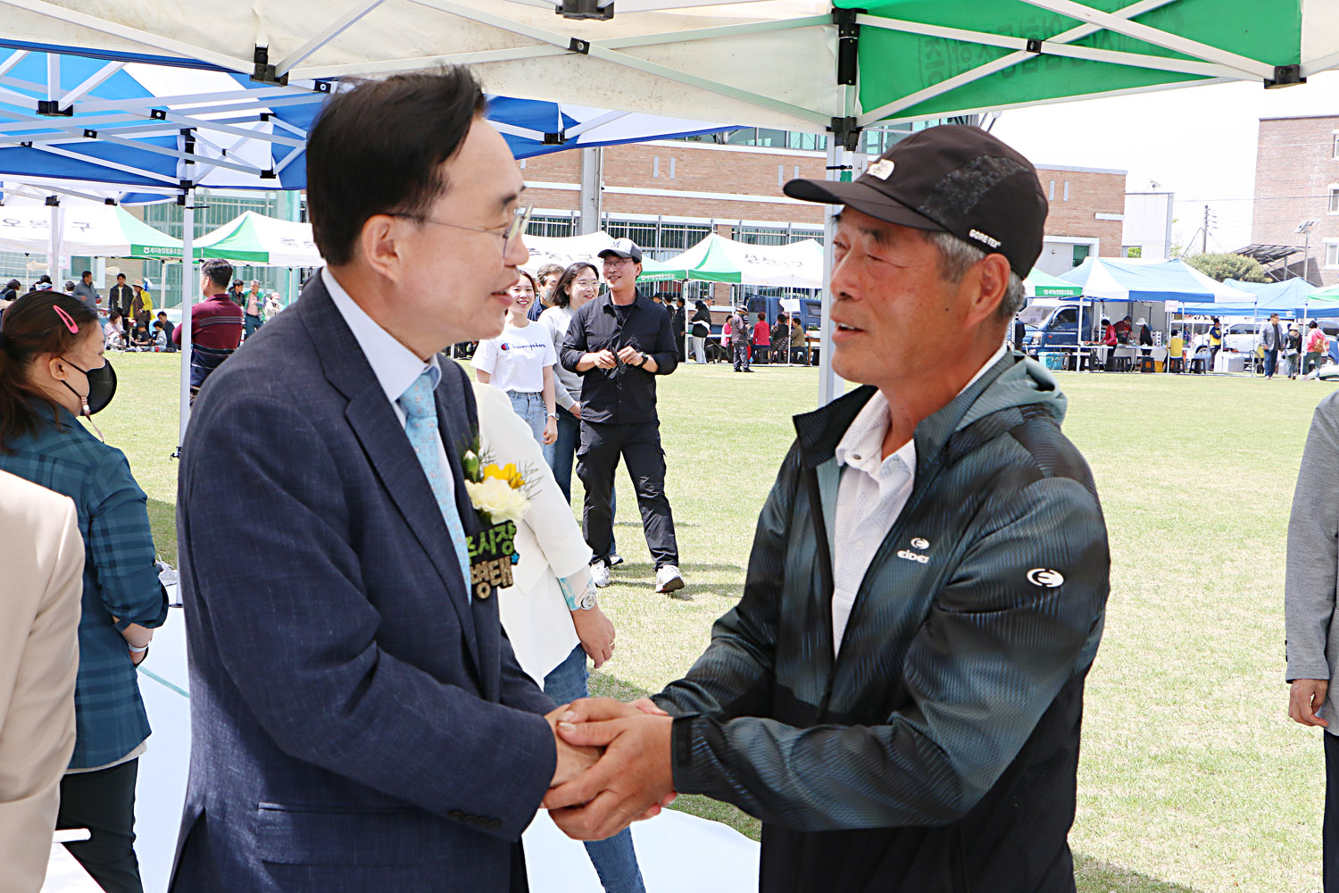 제25회 세지면민의 날 행사 나주시장이 행사장 부스에서 남자 주민분과 악수를 나누며 이야기를 하고 있는 모습