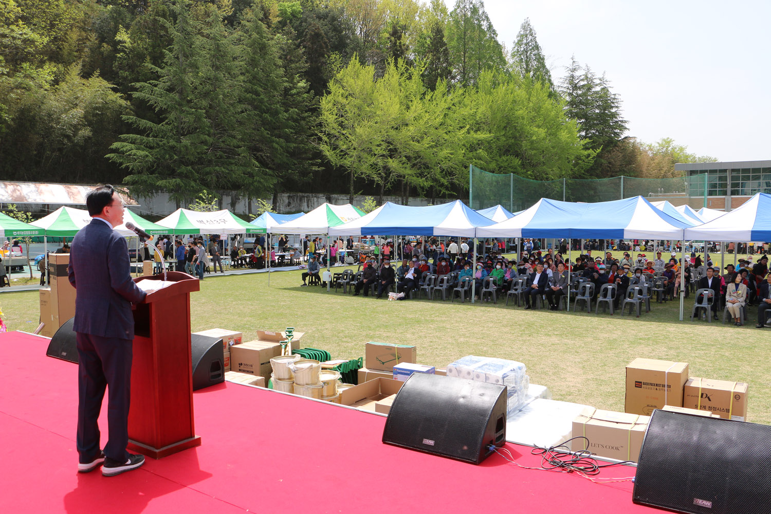 제25회 세지면민의 날 행사 무대 위 나주시장의 우측면 옆모습이 보이고 행사장에 참석한 주민들이 앉아있는 모습이 보이는 전면