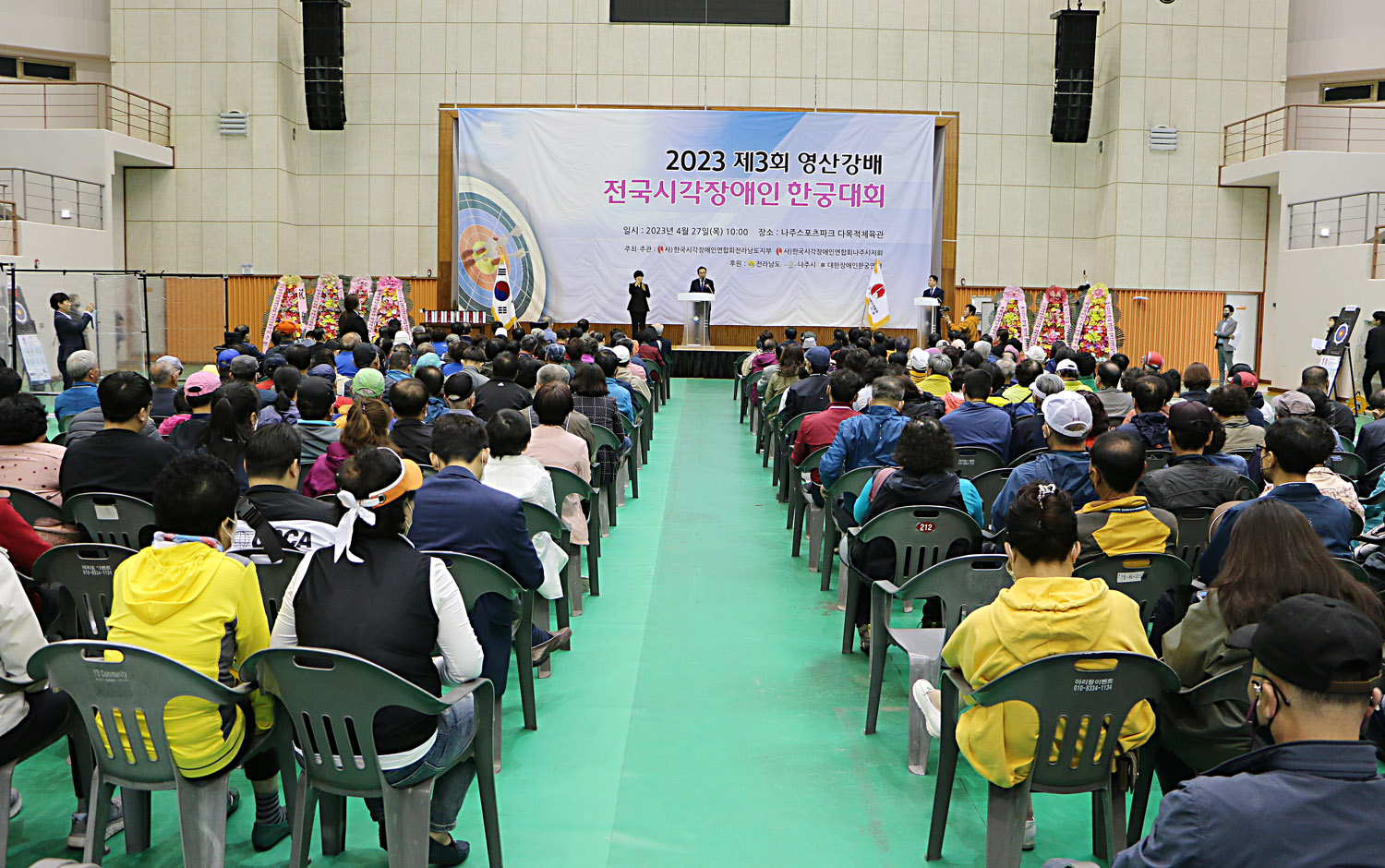 영산강배 전국 시각장애인 한궁대회 개회식 참석자들의 앉아있는 뒷모습이 보이고 나주시장이 환영사를 하고 있는 전면