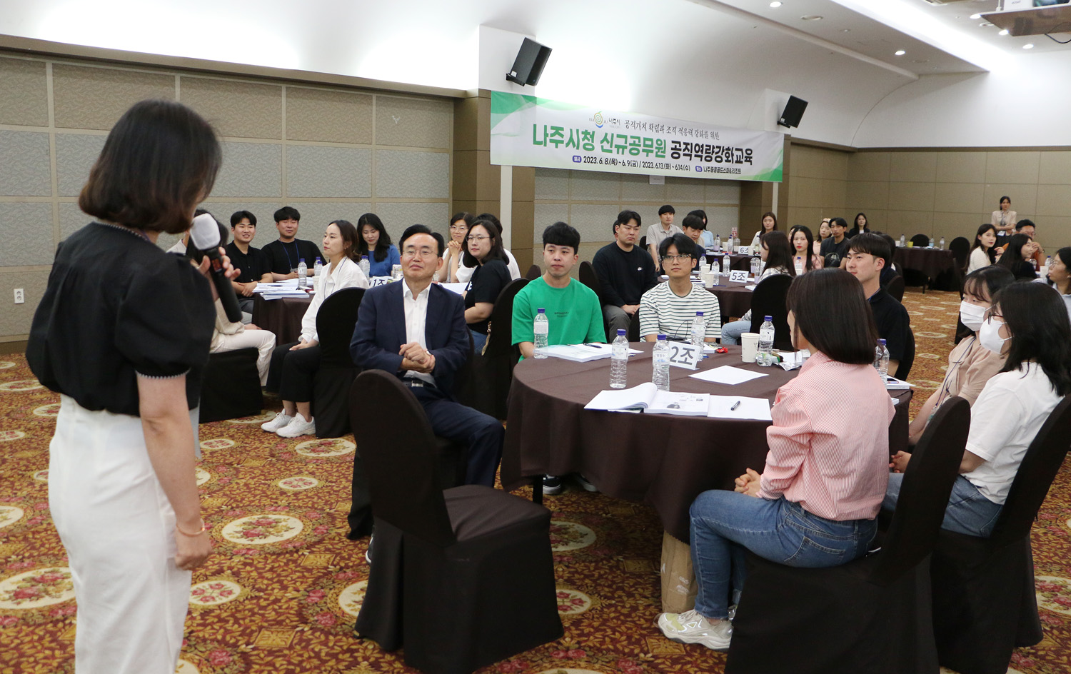 신규임용자 공직역량 강화 교육 강사가 인사말 하는 옆모습이 보이고 신규공무원과 나주시장이 원형테이블에 앉아서 듣고 있는 모습