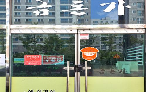 금돈가 입구 문에 금돈가 글씨가 크게 적혀 있으며 국산김치, 천사나눔 인증 스티커가 붙혀있다.