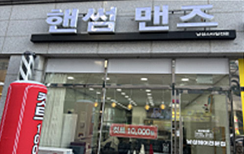 핸썸 맨즈라고 쓰여진 하얀색 간판이 붙은 건물 유리창에 컷트 10,000원 이라고 쓰여진 현수막이 걸려있다.