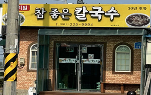 노란색바탕의 간판에 우리밀 참 좋은 칼국수 30년 전통이 크게 적혀 있고 하단에 가게 번호 061-335-9994가 검정색 글씨로 적혀있다.