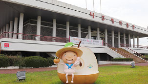 나주배박물관 전경으로 사각의 지붕아래 둥근기둥들이 무수히 둘러싸고 있으며 입구에 나주배를 들고있는 캐릭터 동상이 있다.