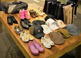 평상위에 신발과 모자가 놓여져 있고 그 그옆에 옷과 바지가 행거에 걸려있다