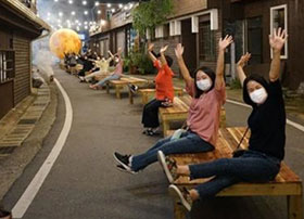 평상위에 나란히 사람들이 양손을 들고 만세 하고 있는 모습