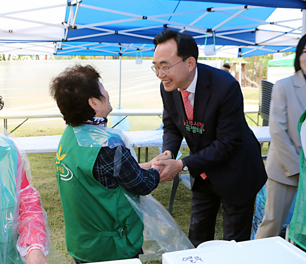 제6회 성북동민의 날 행사 나주시장이 행사장 부스의 여성분과 악수를 하며 인사를 나누는 모습