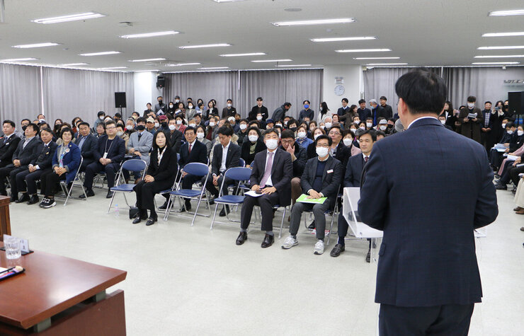 빛가람동 주민과의 대화 대화장 앞쪽에서 나주시장의 인사말 뒷모습과 참석 주민들의 모습이 보이는 장면
