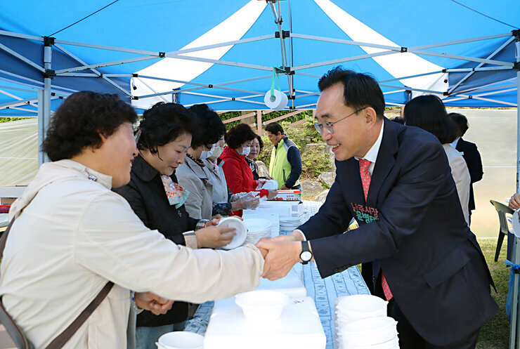 제6회 성북동민의 날 행사 행사장 부스에서 음식 준비를 하고 있는 여성 분과 손을 잡고 인사를 나누는 나주시장 모습