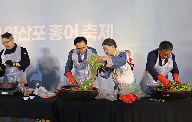 제19회 영산포 홍어축제 개막행사 메인 무대 위 나주시장이 홍어무침을 하기 위해 고무장갑을 끼고 준비를 하고 있는 모습 옆에서 진행자가 미나리를 부어주고 있는 모습