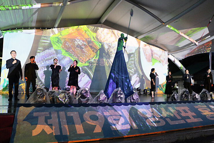 제19회 영산포 홍어축제 개막행사 나주시립  합창단의 무대 위 공연 모습 중앙에 천으로 높게 형상화 된 사람이 노를 젓는 퍼포먼스도 함께 진행되고 있다
