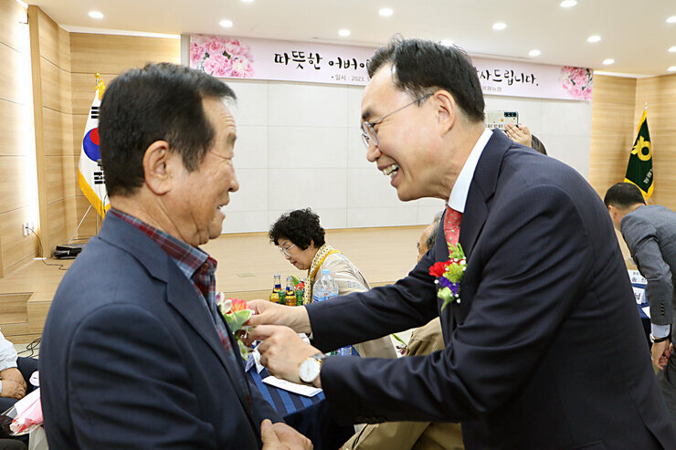 제51회 봉황면 어버이날 기념행사 남자 어르신에게 이벤트로 카네이션을 달아 드리며 인사를 나누는 모습