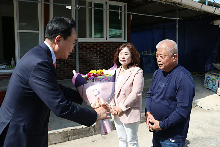 따뜻한 보금자리 3호 주택 준공식  나주시장이 주택 공사 담당 대표 2명에게 꽃다발을 증정하고 있는 모습