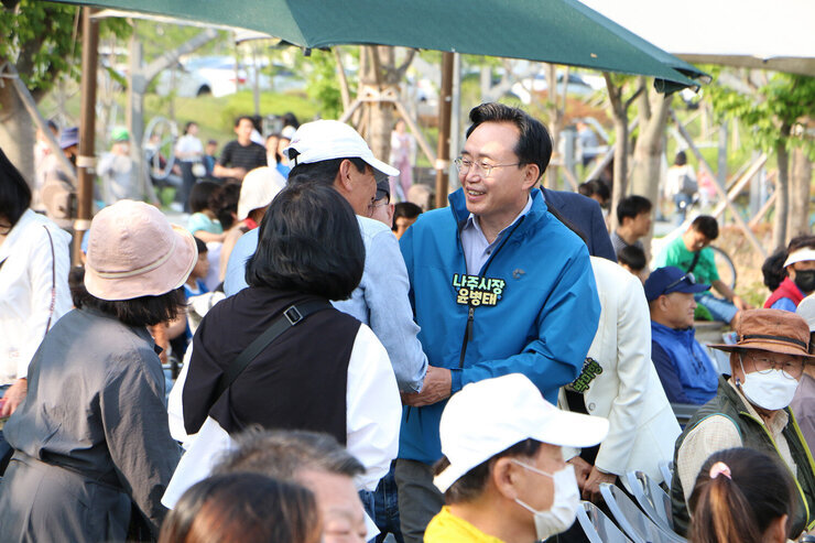 광주, 전남 공동혁신도시 발전기원 건강걷기대회 나주시장이 개회식에 앞서 한 남성과 손을 맞잡으며 인사를 나누는 모습