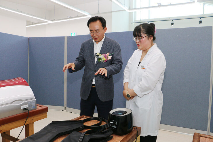 동강대전보건진료소 개소식 나주시장이 보건진료소 내부의 다리 맛사지 기기를 보며 진료소장과 함께 대화를 나누고 있는 모습