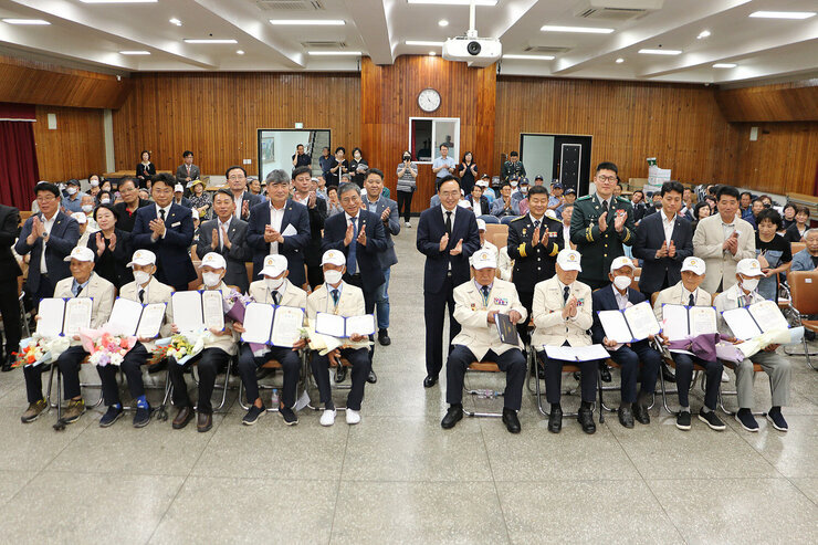 제73주년 6.25전쟁 상기행사 참전자회 회원 분들이 앞자리에 앉아 있고 그 뒤에 나주시장과 시의회 의장, 경찰서장 등 관계자들이 서서 박수를 치고 있는 모습