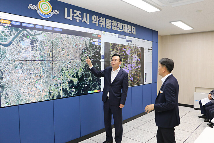 악취통합관제센터 개소식 나주시장이 담당 과장과 함께 관제센터 화면 앞에 서서 관제 시스템에 대해 대화를 나누고 있는 모습