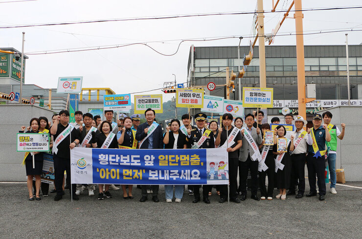 민, 관, 경 합동 어린이 교통안전 캠페인 나주시장과 교통행정과 직원, 나주경찰서장 및 관계자들이 현수막을 펼치고 기념촬영을 하고 잇는 모습