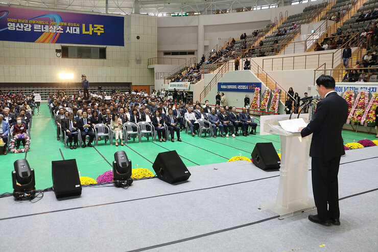 제30회 나주시민의 날 기념식 기념사를 하고 있는 나주시장의 좌측 뒷편에서 촬영한 모습 참석자들이 자리에 앉아 있는 앞모습이 보인다