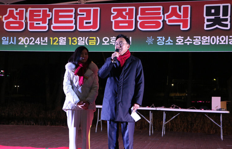 성탄트리 점등식 나주시장이 무대 위에서 인사말을 하고 있는  묘습 옆에 배우자가 함께 서 있는 모습