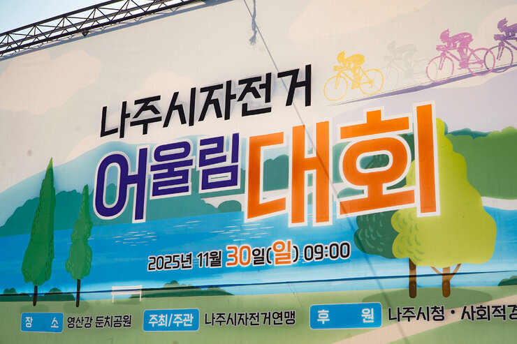  '나주시자전거 어울림대회'라고 크게 적힌 현수막. 개최일시는 '2025년 11월 30일(일) 09:00', 장소는 '영산강 둔치공원', 주최/주관은 '나주시자전거연맹', 후원은 '나주시장청 사회적경' 등으로 적혀 있다.