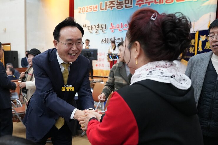  윤병태 나주시장이 한 중년 여성 참석자와 악수를 나누며 활짝 웃고 있는 모습