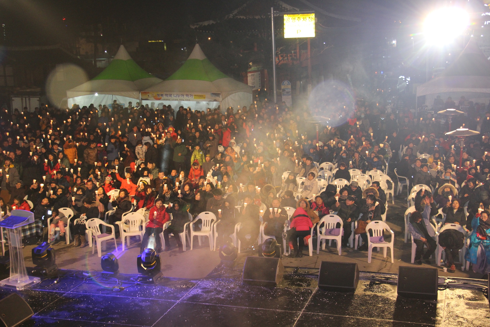 스테이지에서 바라보는 행사 관객들이 의자에 다 앉아 있고 촛불을 하나씩 들고 있는 모습