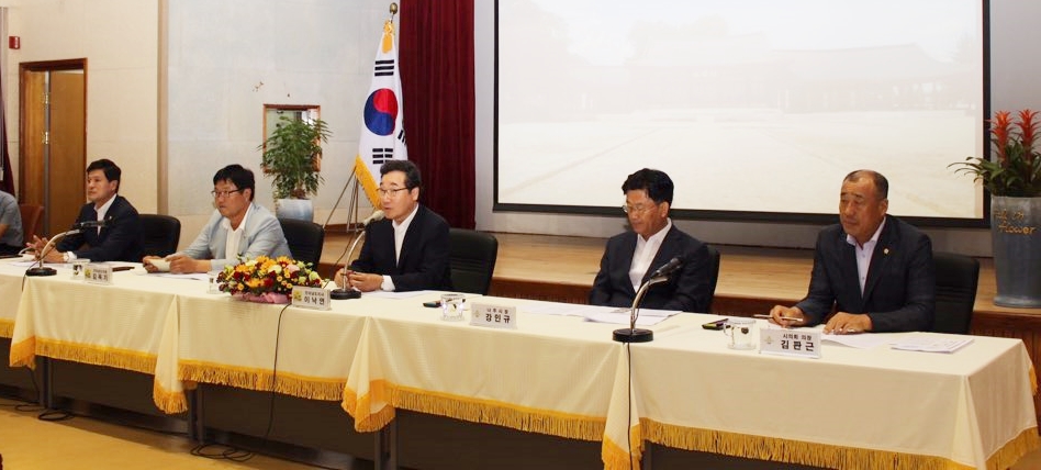 회의실 앞 단상에 앉아서 연설하는 모습