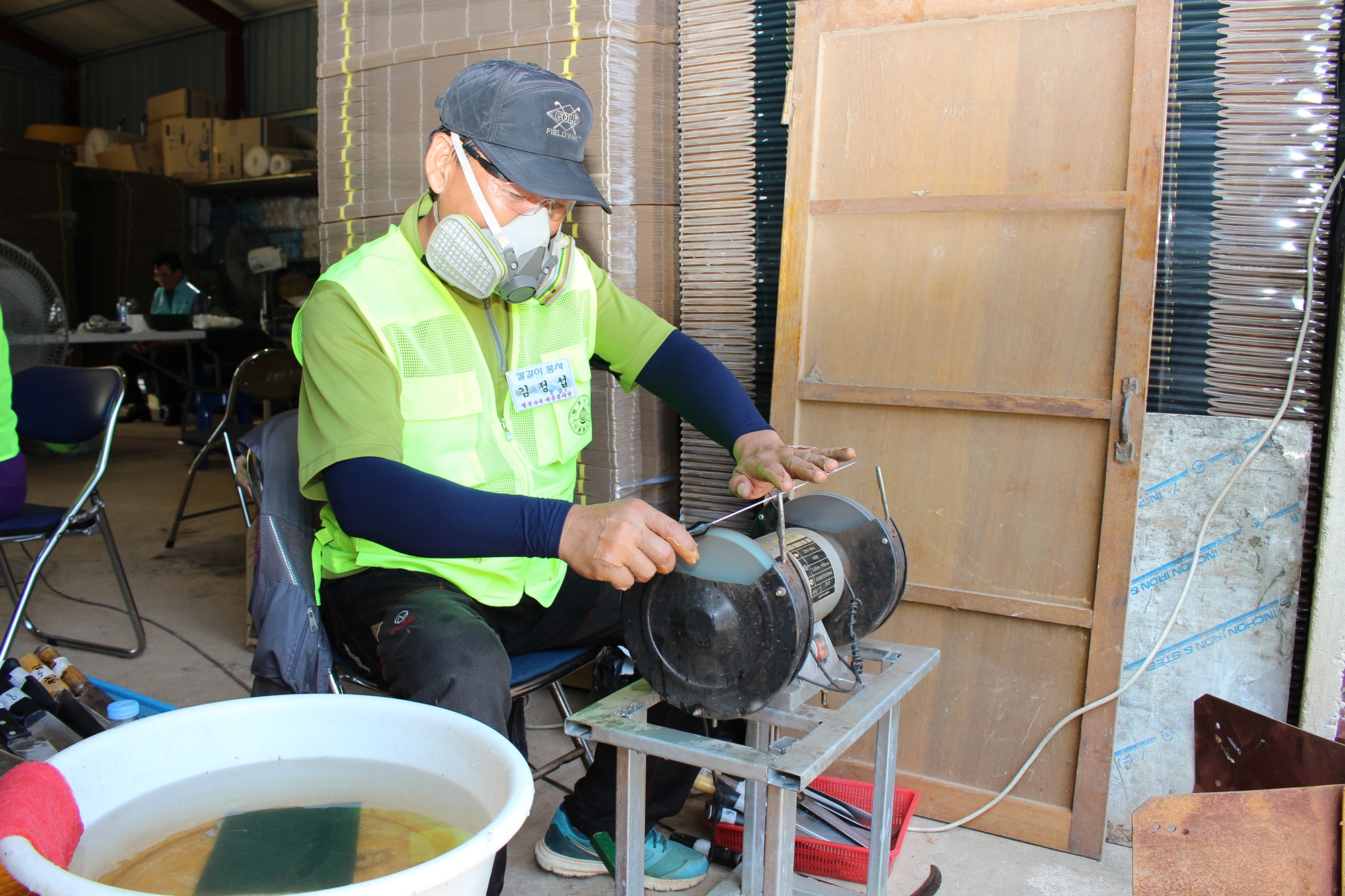 의자에 앚아 기계를 수리하는 봉사단의 시민한분