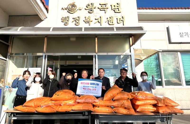 왕곡면 행정복지센터' 앞에서 여러 사람이 주먹을 쥐고 서서 주황색 포대에 담긴 백미 앞에서 기념 촬영을 하는 모습. 포대 위에 올려진 흰색 종이에는 '이웃사랑 희망나눔'과 '백미 20kg 20포'가 적혀 있다. 건물 상단에는 'NAJU 왕곡면 행정복지센터'라는 글씨가 보인다.