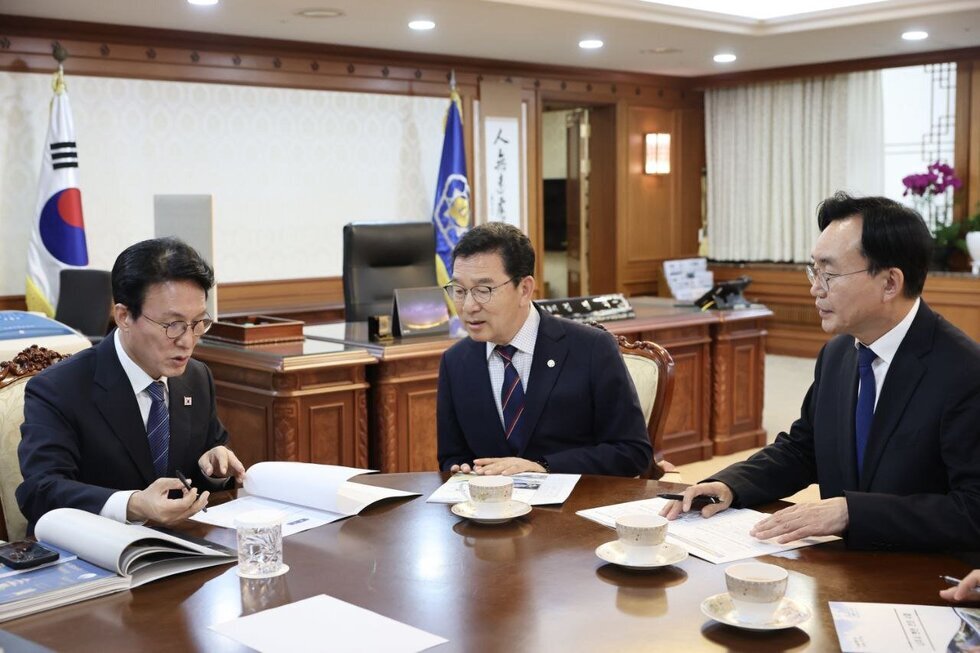  실내 사무실로 보이는 곳에서 세 명의 남성(오른쪽 끝 나주시장 윤병태)이 테이블에 둘러앉아 서류를 보며 대화하고 있는 모습. 테이블 위에는 찻잔과 서류가 놓여 있다.