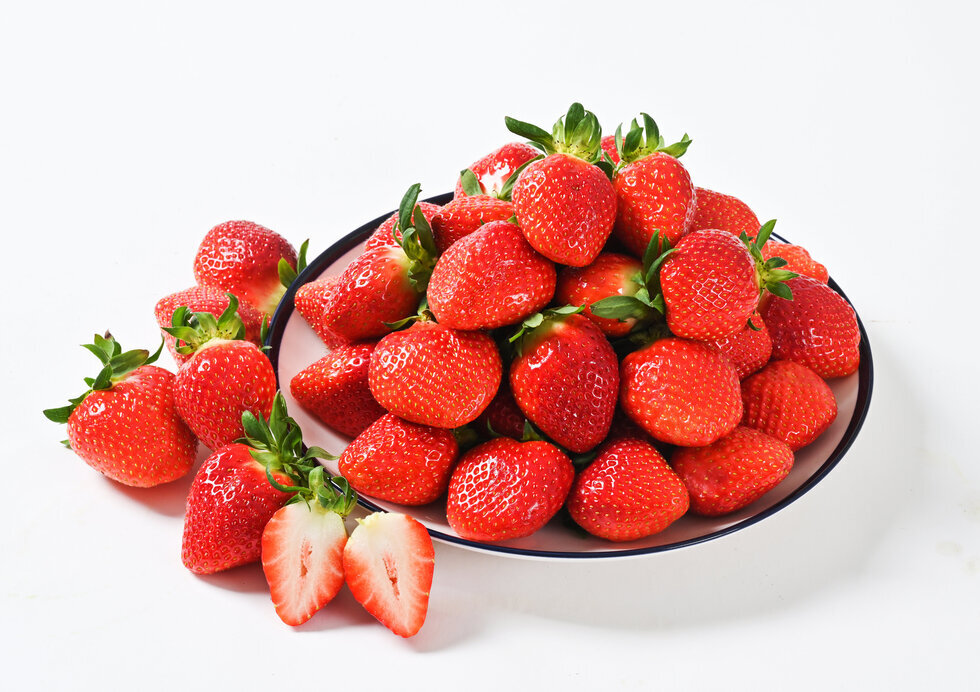 접시에 쌓여있는 딸기와 접시 앞에 놓여있는 딸기