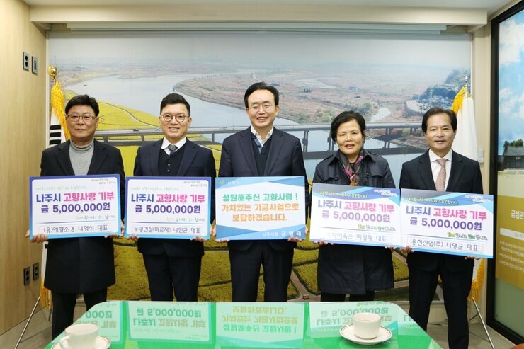 가운데 시장님이 성원해주신  고향사랑! 가치있는 기금사업으로 보답하겠습니다. 라고 적힌 팻말을 들고 양 가에 나주시 고향사랑 기부 금 5,000,000원 (유)예향조경 나영식 대표, 토광건설(미르채) 나안균대표, (주)하이옥스 이영례대표, 용천산업(주) 나명균대표 이라고 적힌 팻말을 각각 들고 사진찍고 있다.