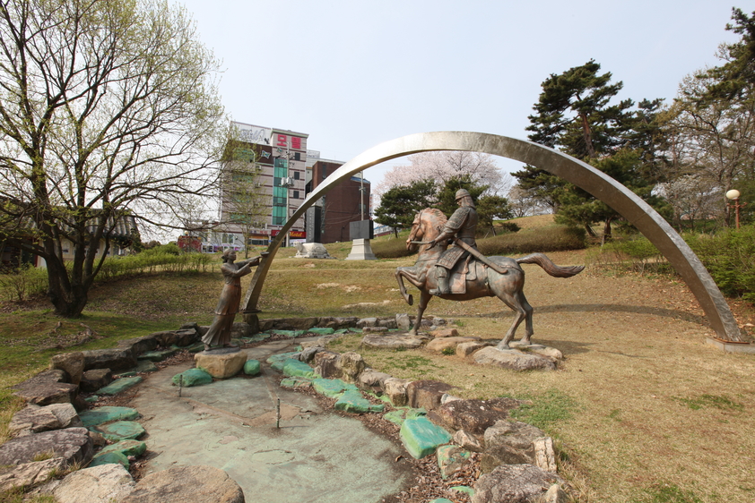 완사천에 전경을 찍은 사진. 잔디밭 사이로 말을탄 장군복을 입은 동상과 여인의 동상이 보이며 완사천에 물이 말라 있음.