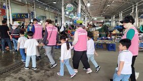노인일자리 활동모습 분홍색 조끼활동복을 입은 어르신들이 흰색 티셔츠에 청바지를 입은 아이들의 손을 잡고 인솔하고 있다