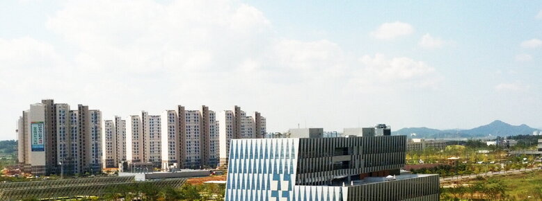 특이한 패턴의 건물을 뒤로 아파트 단지가 보이는 사진