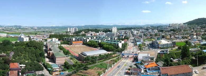 도로를 기점으로 왼쪽에는 학교운동장 오른쪽에는 건물들이 보인다