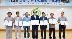 귀농귀촌 선도마을 조성사업 워크숍 나주시장과 선도마을로 지정된 6개마을 추진위원장들이 협약서를 들고 기념촬영을 하고 있는 모습