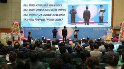 제6회 이, 통장 한마음대회 무대 위 에서 남성, 여성 대표자가 헌장 낭독을 하고 있는 모습과 참석자들이 앉아 있는 뒷모습