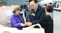 봉황농협 APC 수매현장 방문 나주시장이 톤백 앞에서 여성 농민 분과 손바닥에 올린 미곡을 살펴보고 있는 모습