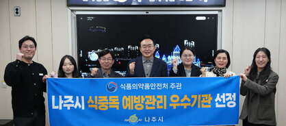  윤병태 나주시장(가운데)과 시청 직원들로 보이는 남녀 7명이 '식품의약품안전처 주관 나주시 식중독 예방관리 우수기관 선정 나주시'이라고 적힌 파란색 현수막을 들고 기념사진을 찍고 있는 모습. 모두 주먹을 쥐고 있다.