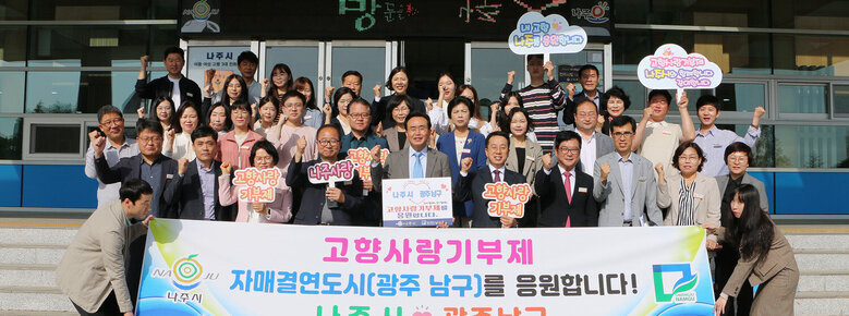 나주시-광주남구 고향사랑기부제 상호 기탁 나주시장과 시청 직원들이 시청 현관 앞에서 기념촐영 하고 있는 모습