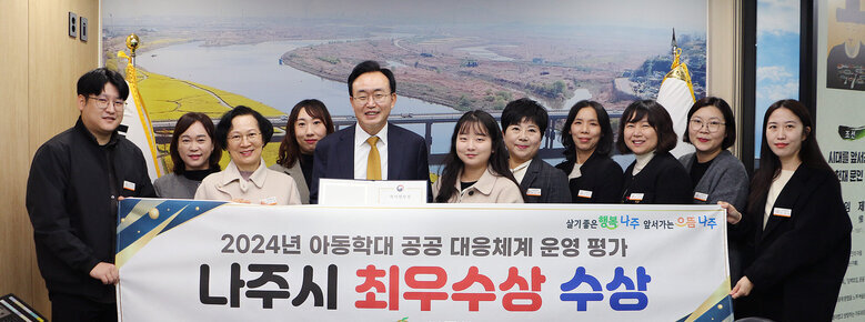 아동학대 공공대응체계 평가 최우수상 수상 나주시장과 아동복지과 간부 공무원 및 직원 10여명이 플래카드를 펼치고 기념촬영을 하고 있는 모습