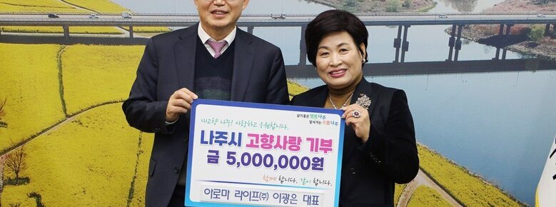   살기좋은 행복 나주 앞서가는 으뜸 나주 내고향 나주! 사랑하고 응원합니다. 나주시 고향사랑 기부 금 5,000,000원 함께 합니다. 같이 합니다. 아로마 라이프(주) 이광은 대표 라고 적힌 팻말을 들고 사진을 찍고 있는 윤병태 시장과 이광은 대표