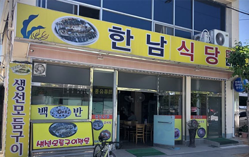 한남식당 입구의 모습 생선모듬구이, 백반, 생선모듬구이등 간판이 있다.
